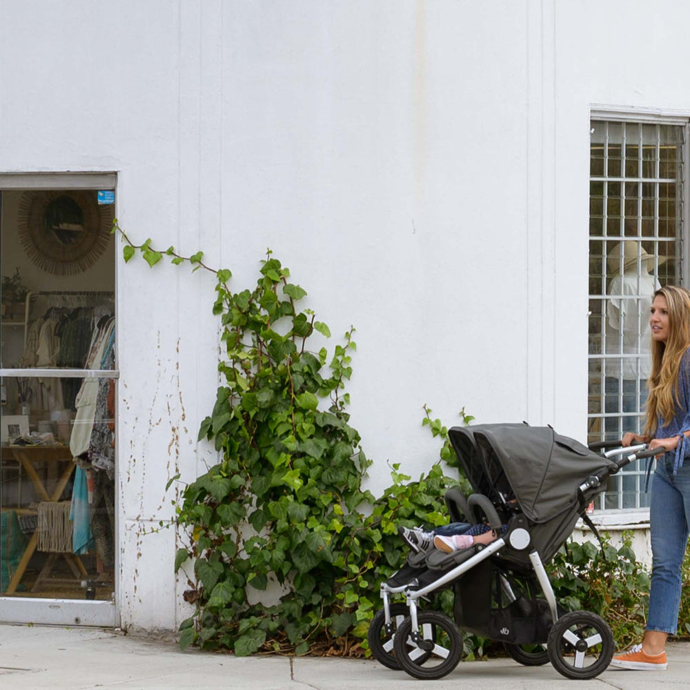 Mother pushing Bumbleride Indie Twin in Dawn Grey in front of storefront on sidewalk