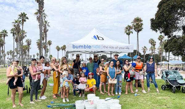 Picture of families holding their toddlers and infants in group photo at Bumbleride and Baby Tula Park Cleanup for Plastic Free July