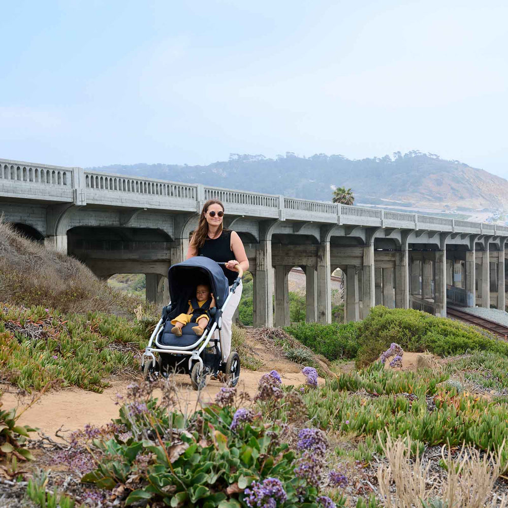
                  
                    Picture of mother pushing Bumbleride Era reversible stroller on dirt trail along coast with ocean and train tracks in background. New Collection 2022 - Global
                  
                
