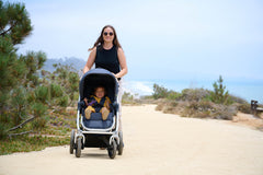 Picture of mother pushing toddler on dirt trail along coast. New Collection 2022 - Global