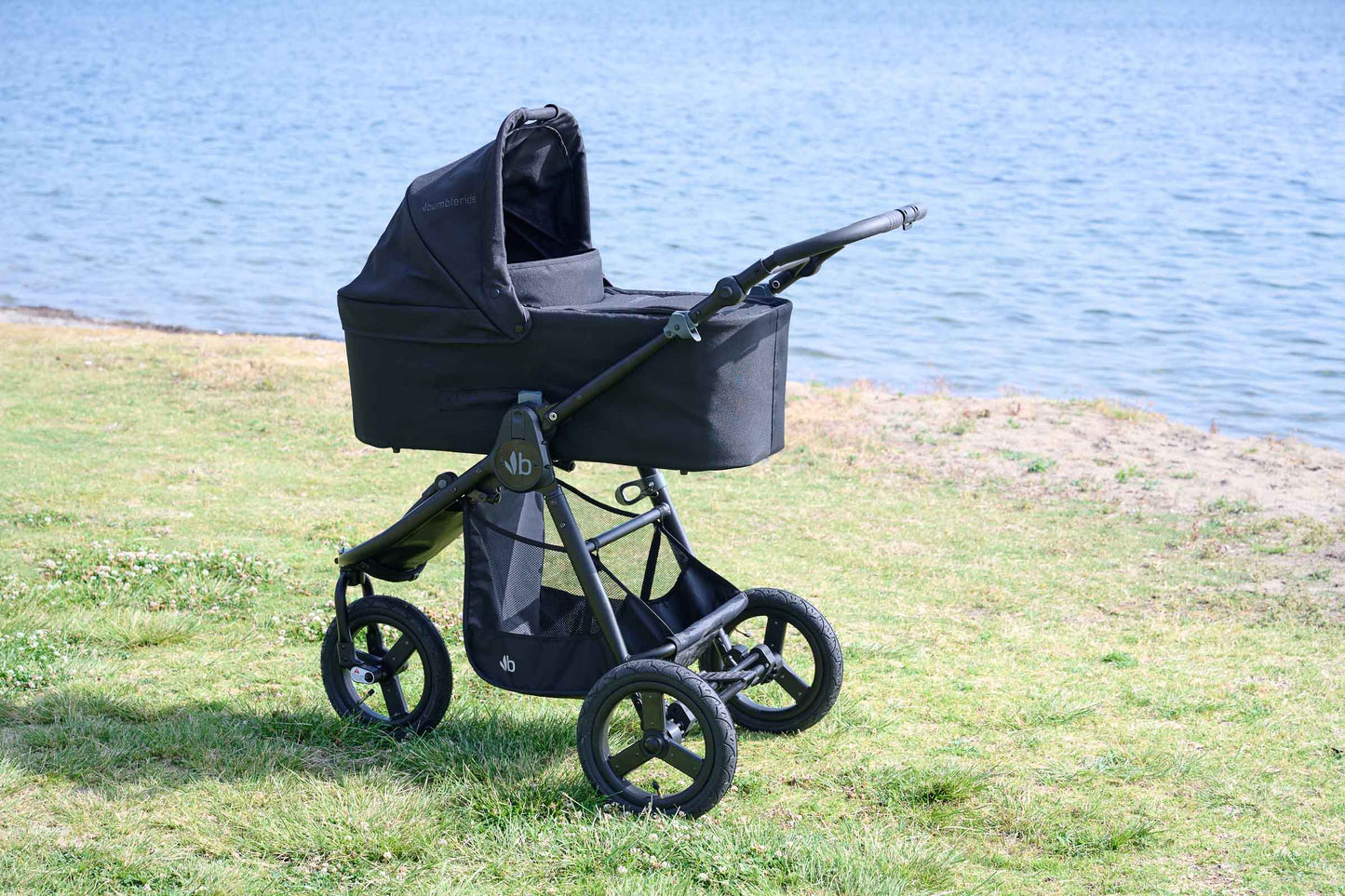 
                  
                    Bumbleride Single Bassinet in Black attached on Bumbleride Indie All Terrain Stroller in Black on grass near water . Global
                  
                