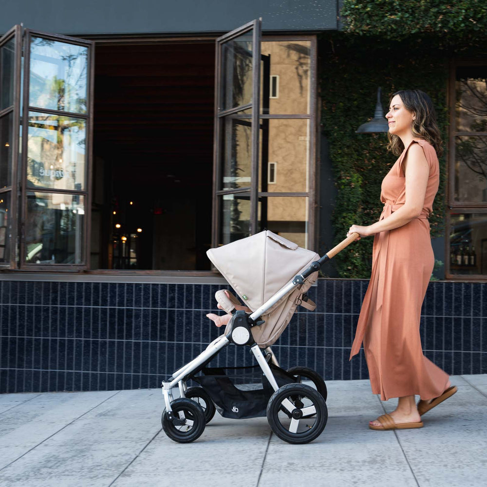 
                  
                    Mother pushing Bumbleride Era reversible stroller in Sand on sidewalk in front of restaurant. New Collection 2022. Global
                  
                