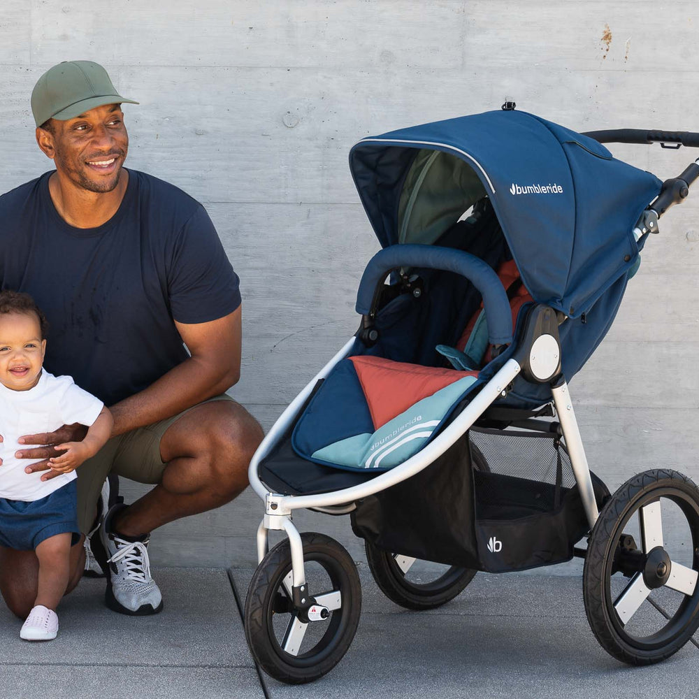 
                  
                    Picture of smiling father kneeling while holding smiling toddler next to Bumbleride Speed jogging stroller in Supernova. New Collection 2022. Global
                  
                