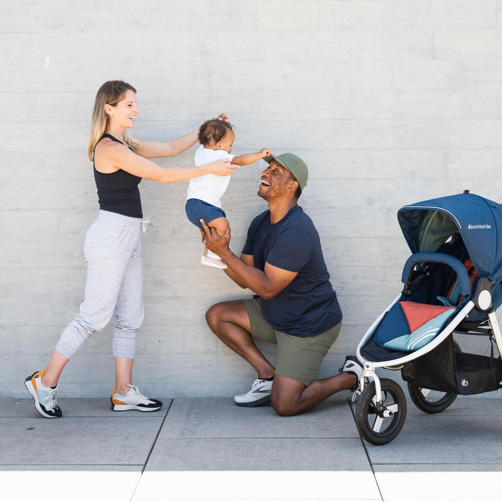 
                  
                    Picture of mother and father playing with toddler in the air while next to Bumbleride Speed jogging stroller in Supernova. Global
                  
                