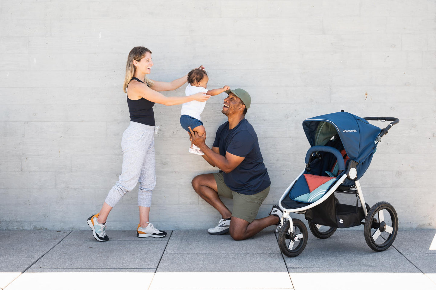 
                  
                    Picture of mother and father playing with toddler in the air while next to Bumbleride Speed jogging stroller in Supernova. Global
                  
                