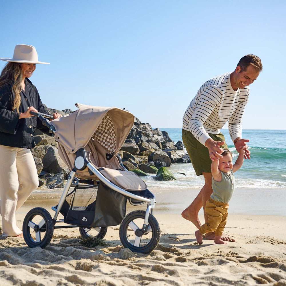 
                  
                    Father holding sons arms on sand at beach with mother walking next to them pushing Bumbleride Indie all terrain stroller in Sand. - New Collection 2022 - Global
                  
                